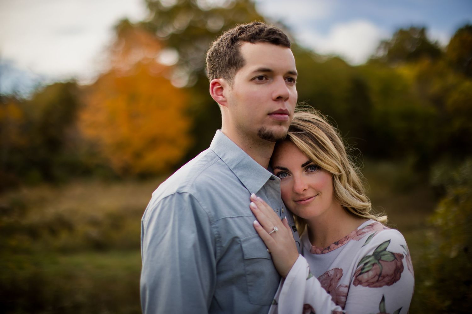 Intimate portrait of a couple against a blurred autumn landscape background.