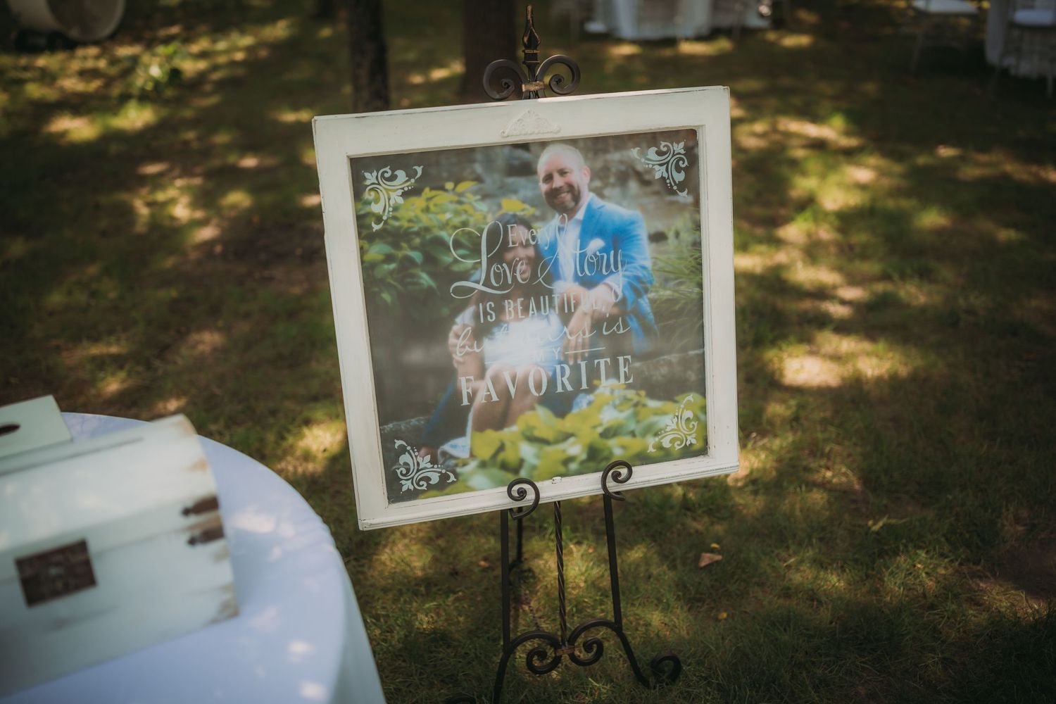 Framed photo displayed on a decorative easel stand at an outdoor event.