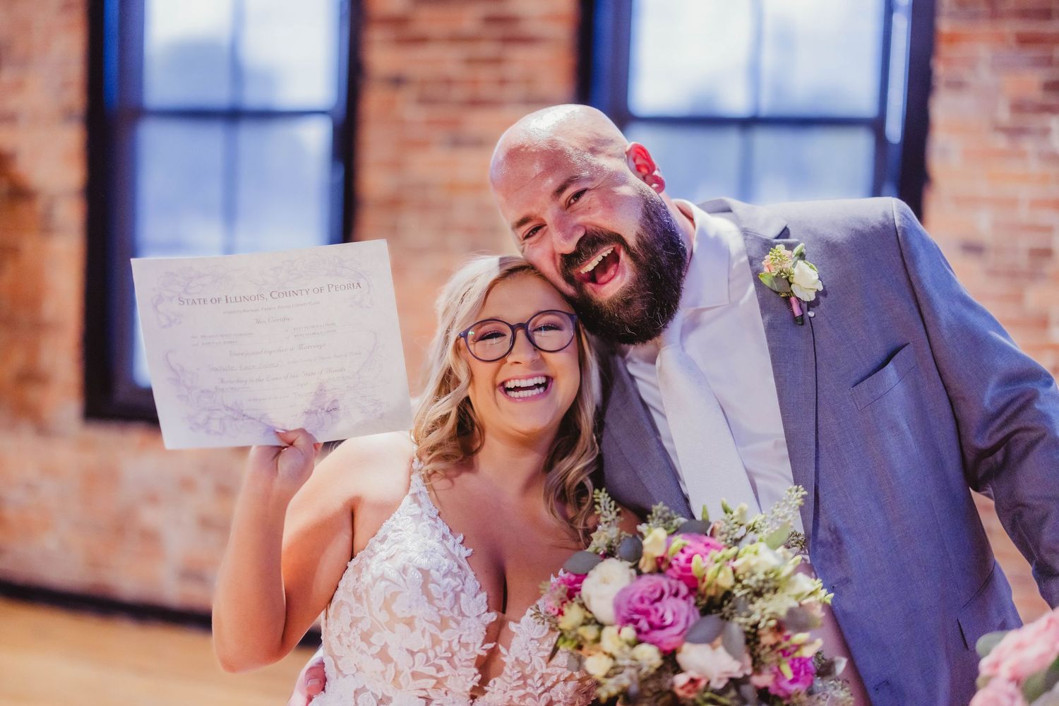 Candid celebration moment in rustic brick venue with natural light streaming through windows.