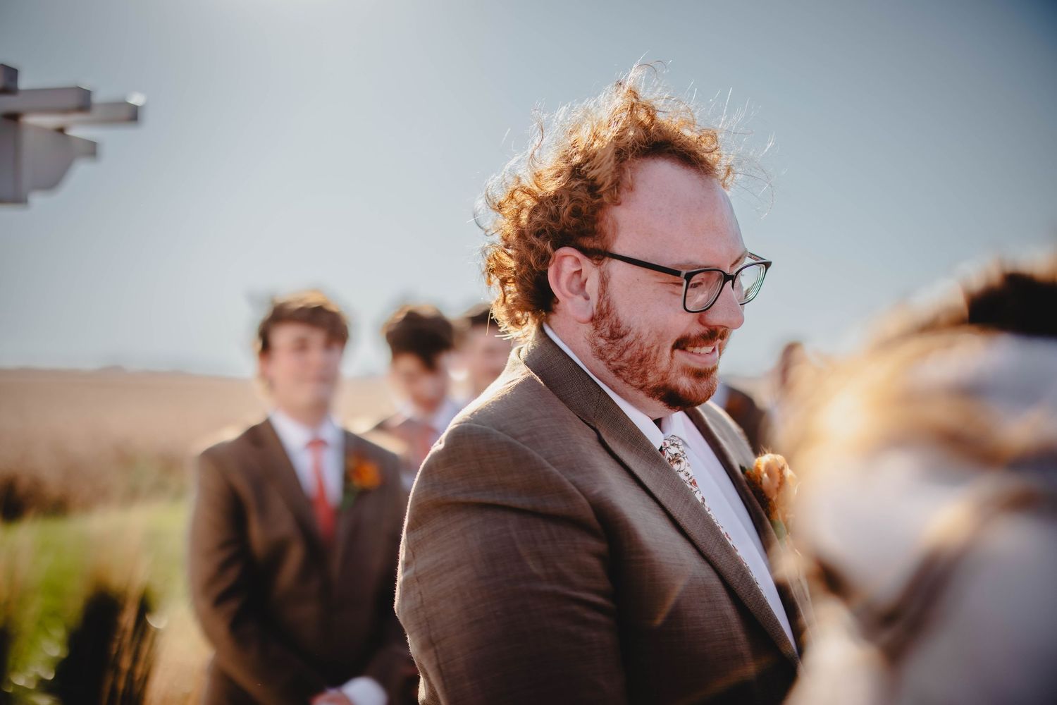 Close-up wedding ceremony shot with rustic white pergola and blue sky.