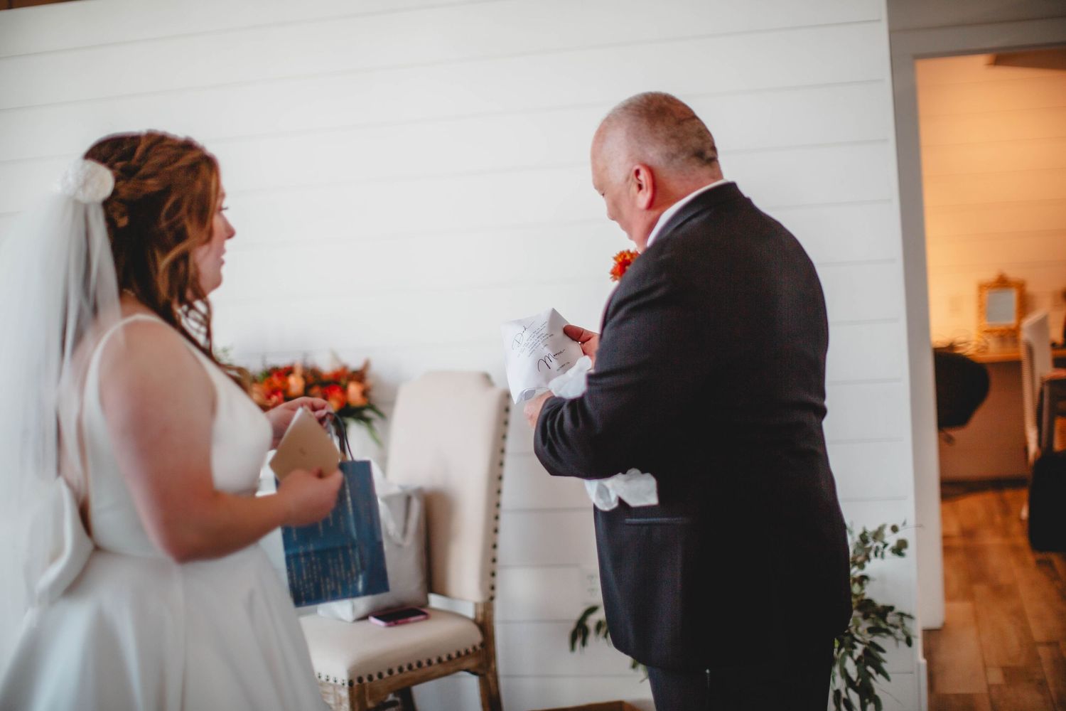 Two individuals reading cards and exchanging messages during an emotional wedding moment.