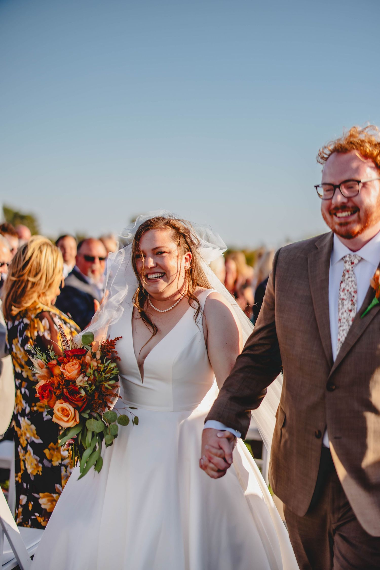 Couple shares laughter during their outdoor wedding recessional.