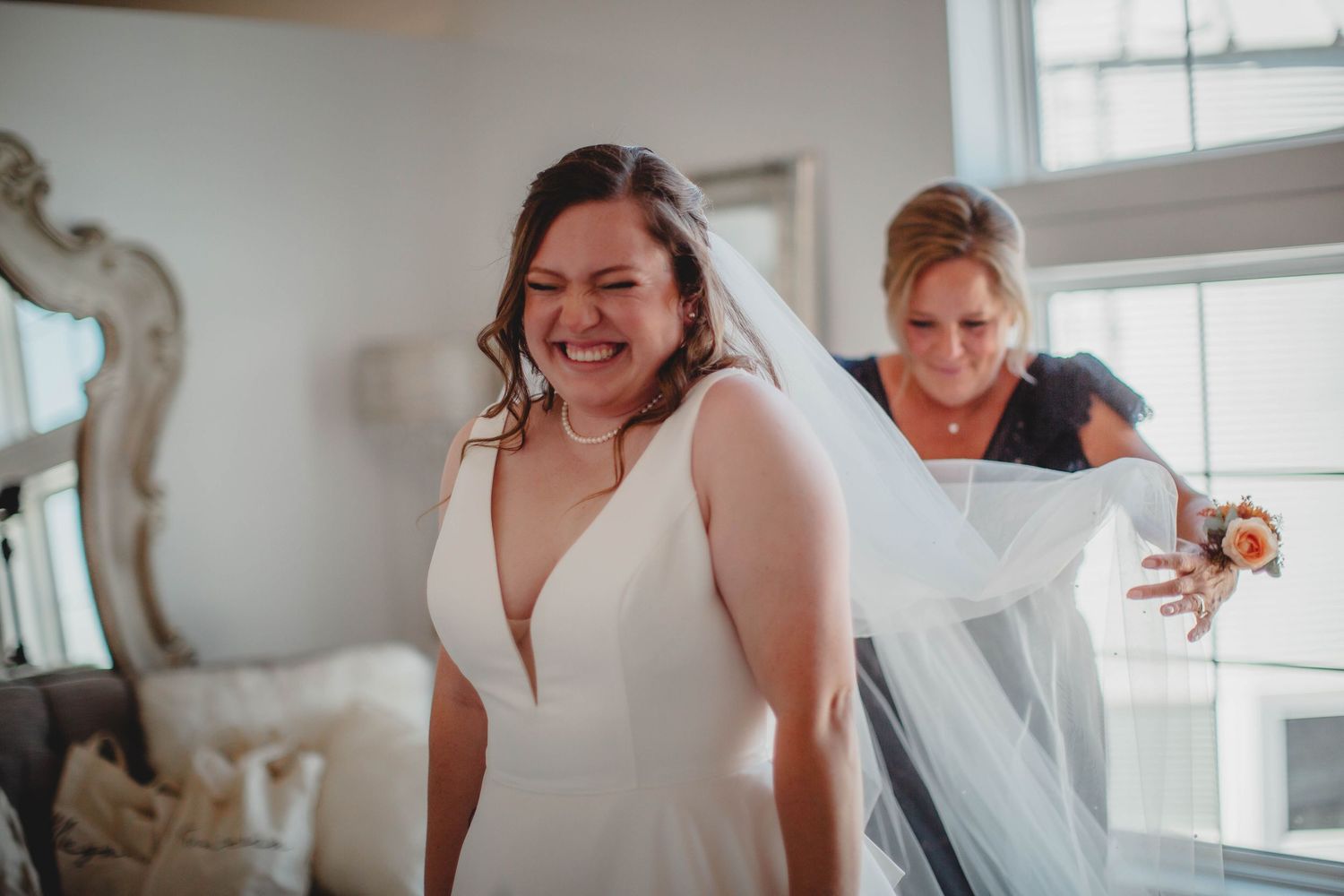 A joyful moment captured during wedding preparations as a veil is adjusted.