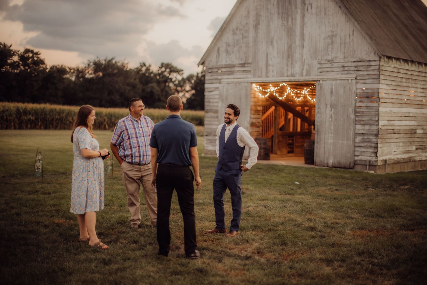 Rustic barn wedding venue at sunset with guests gathered outside.