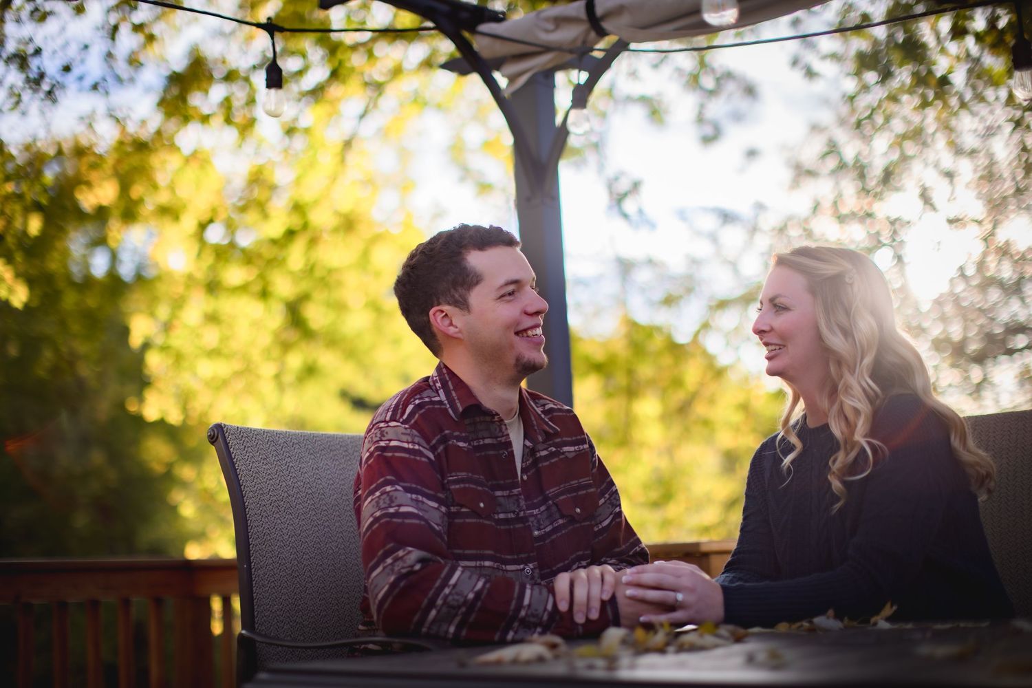 Two people share a romantic moment on an outdoor deck during golden hour.