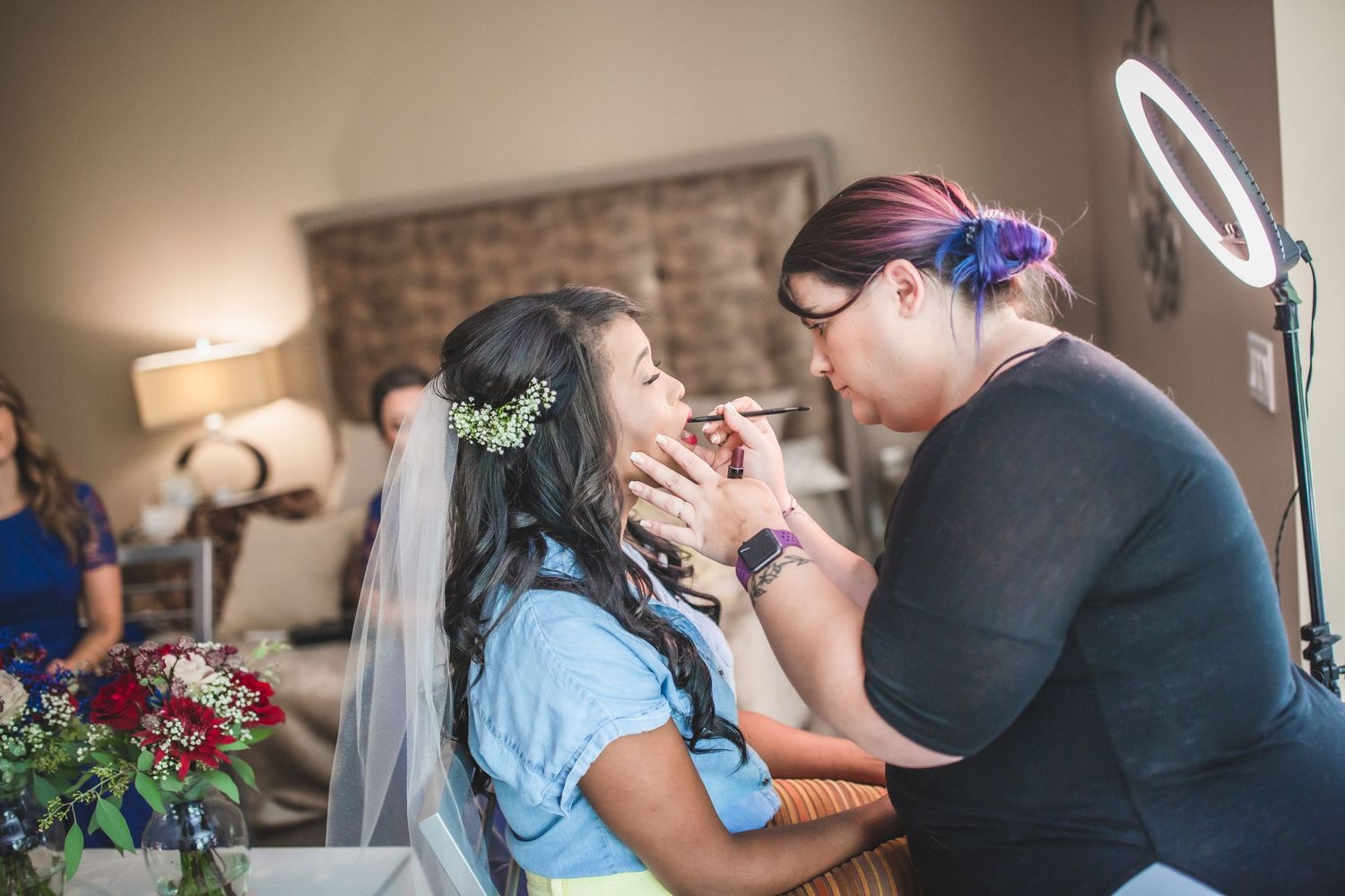 Makeup artist applies cosmetics to bride during wedding preparation.