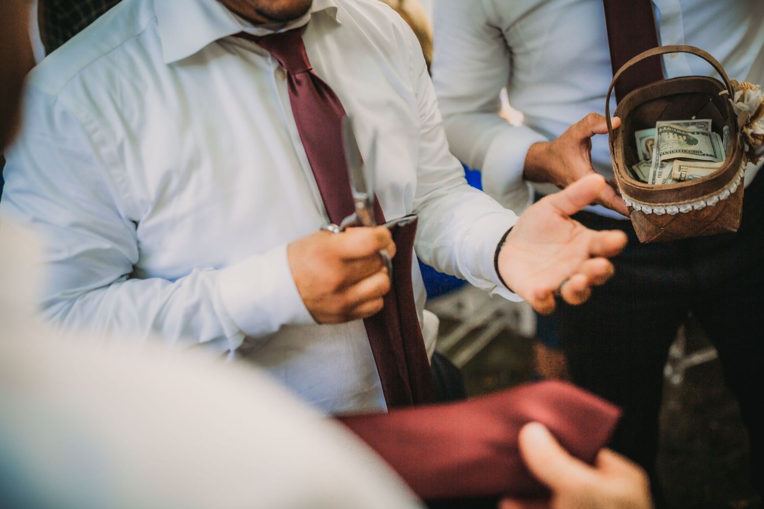 Close-up detail of formal attire with white shirt and burgundy tie at a wedding reception.