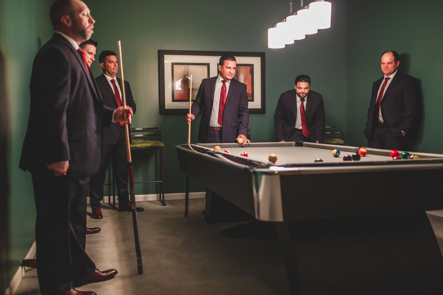 Business professionals gathered around a pool table in a room with modern lighting and artwork.