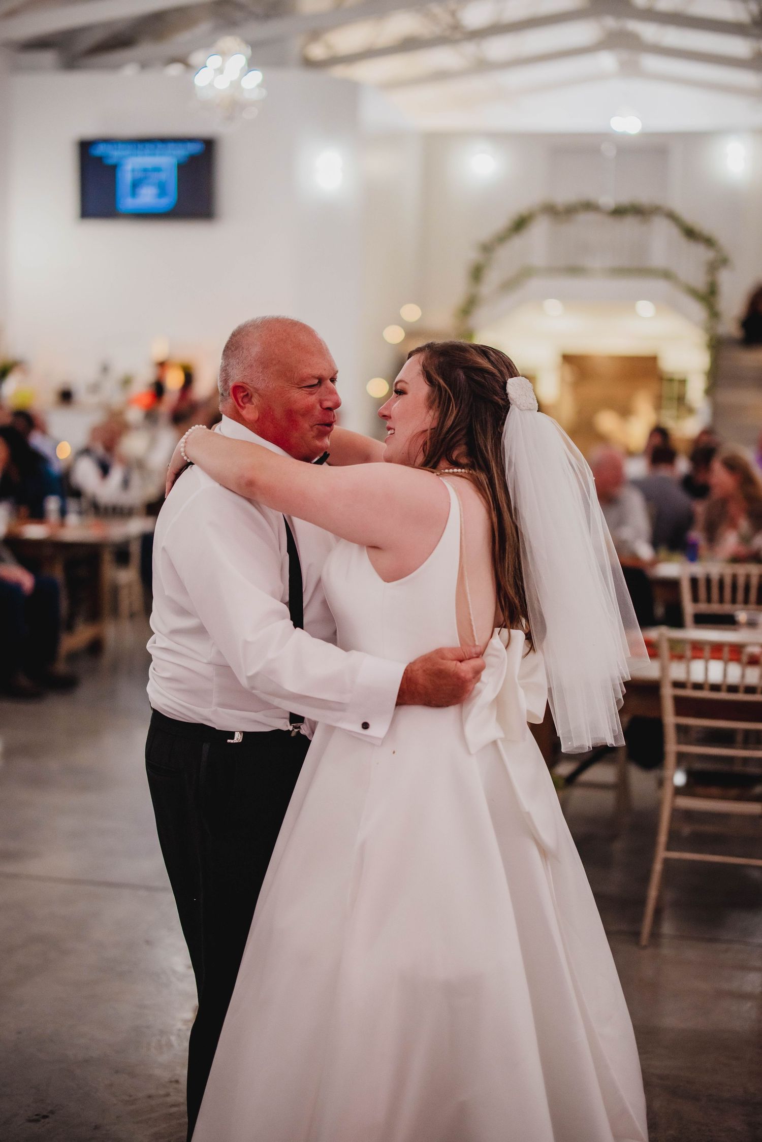A bride and her dance partner share an emotional moment during their wedding dance in an elegant reception venue.