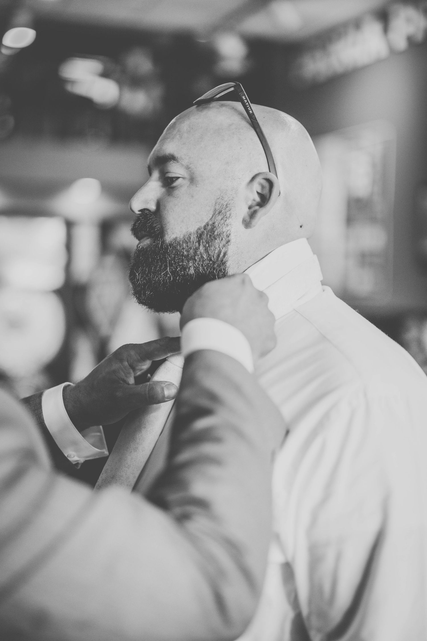 Black and white photo of someone getting their tie adjusted before formal event.