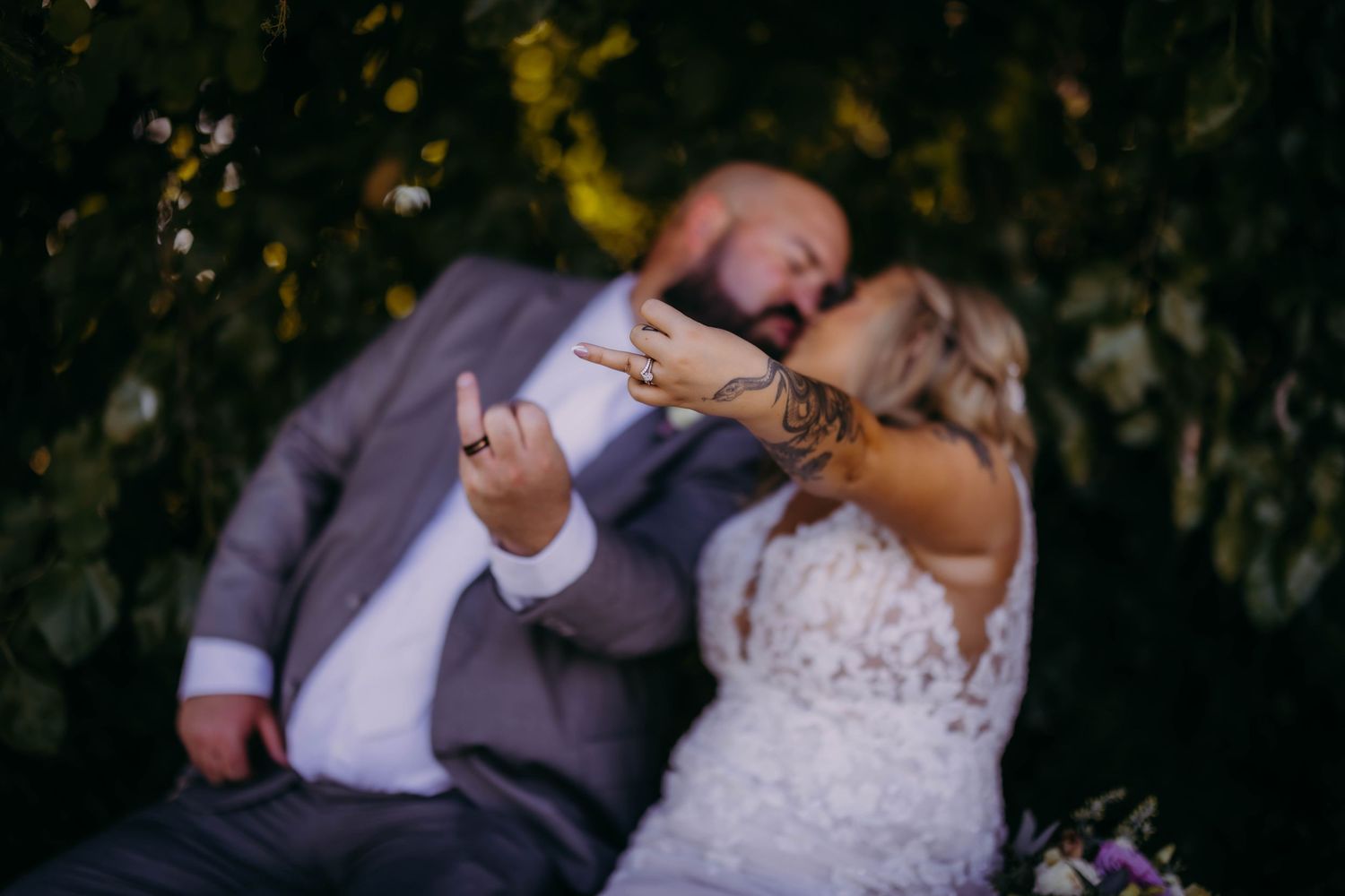 A playful wedding moment captured as the couple laughs together on a bench.