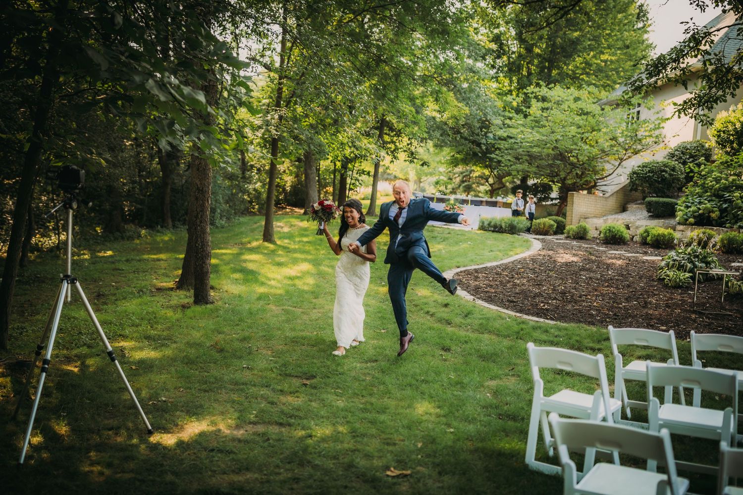 Playful couple skips down the garden aisle after their outdoor ceremony.
