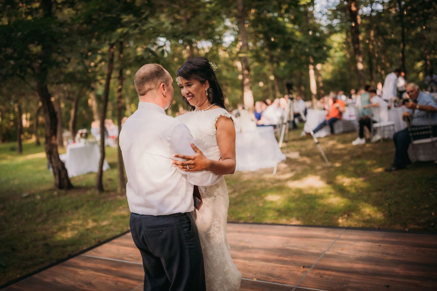Newlyweds share an intimate dance moment on their outdoor wooden dance floor at sunset.