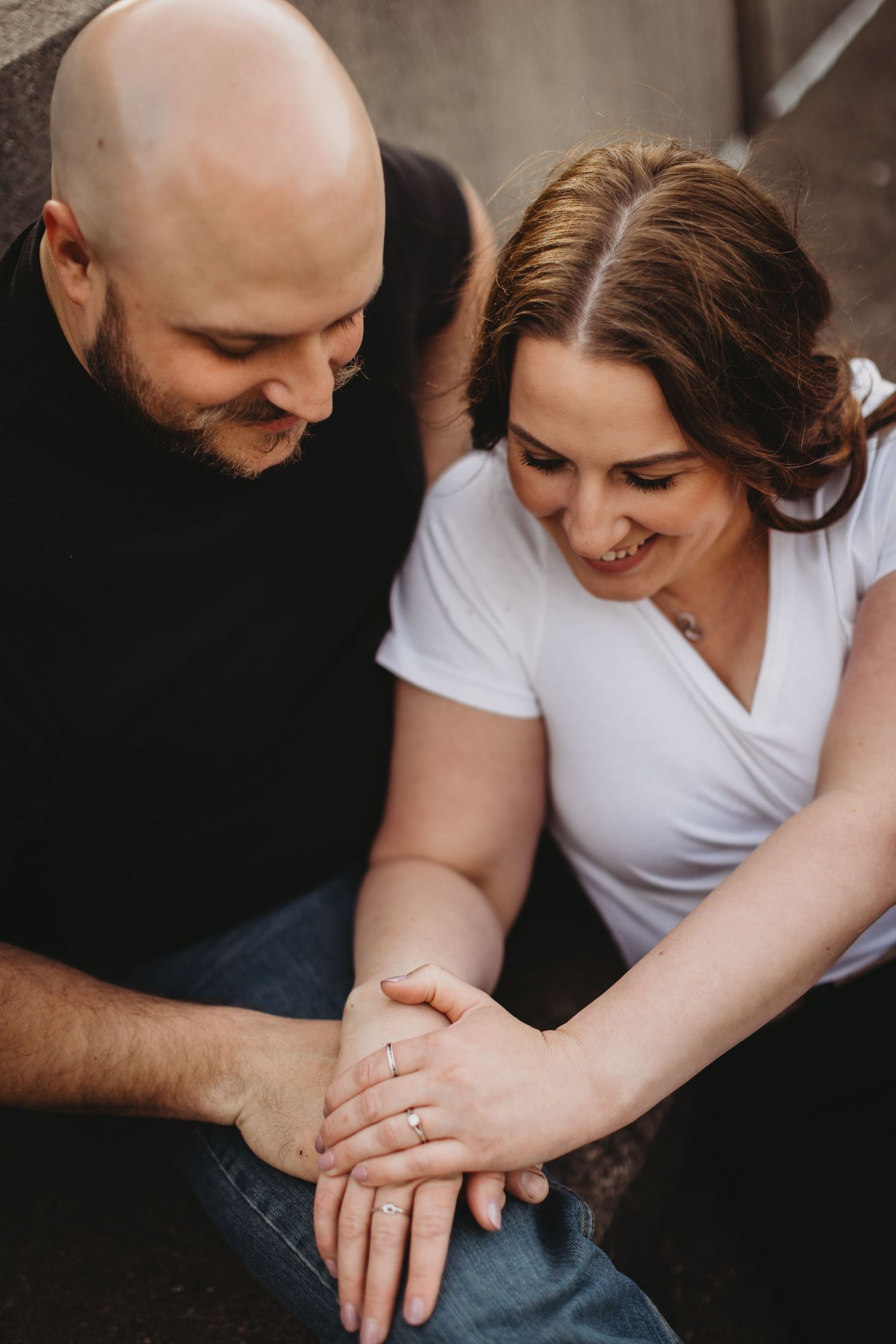 A close-up portrait of a couple holding hands and laughing together.