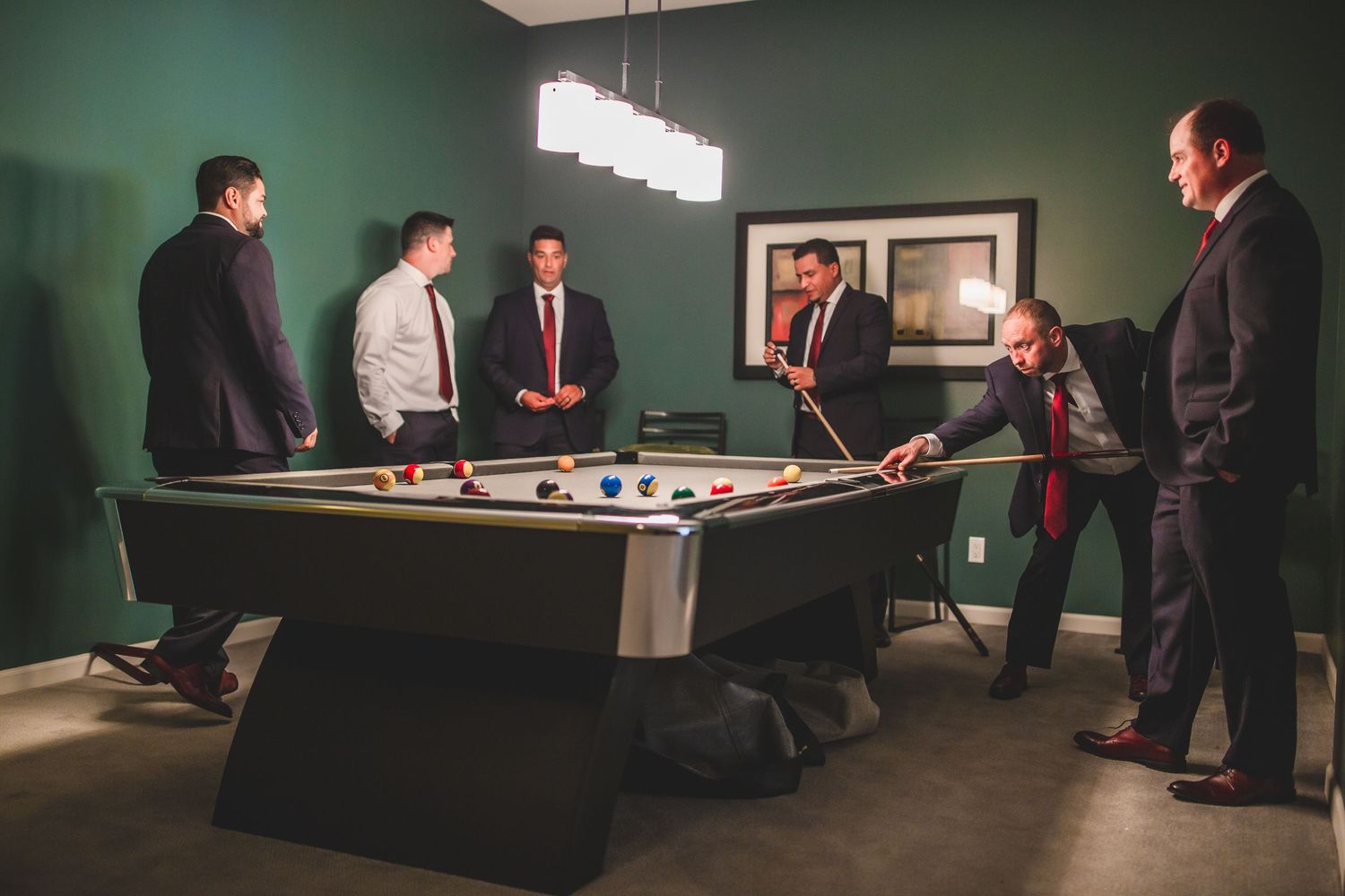 A group playing billiards in a stylish room decorated with modern lighting and wall art.