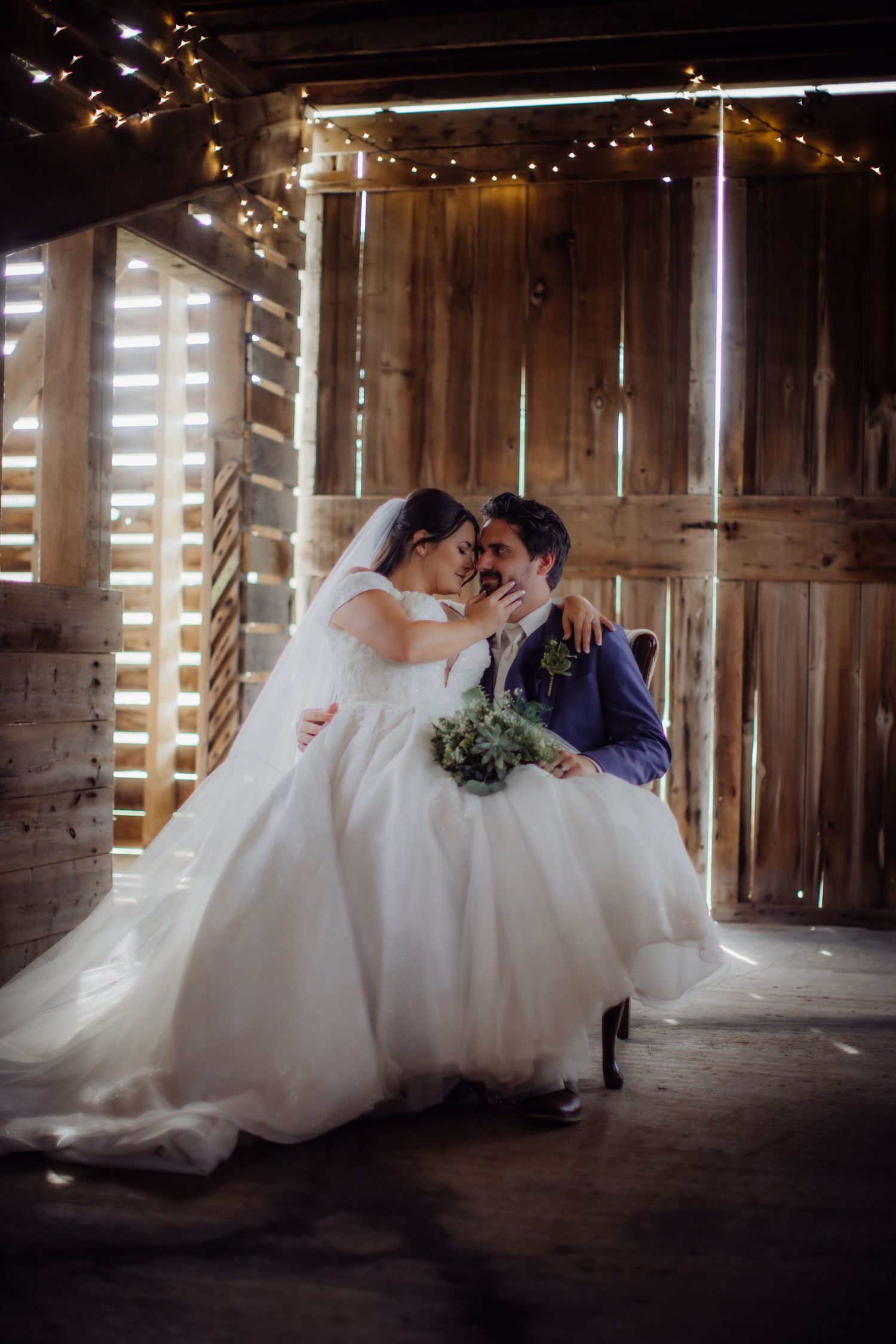 Romantic barn wedding scene with string lights and a couple in elegant attire.