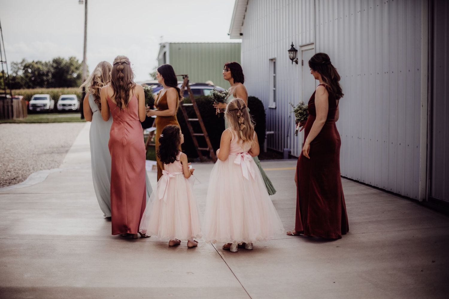 Group of wedding attendees in formal dresses gathered outside venue.