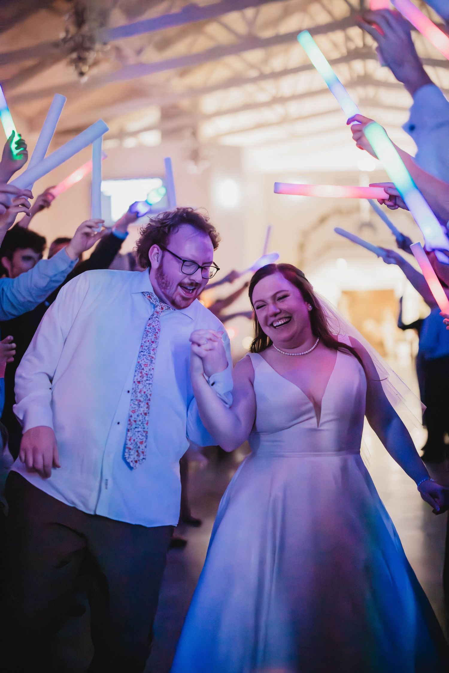 A festive wedding dance moment captured with glowing light sticks and joyous celebration.