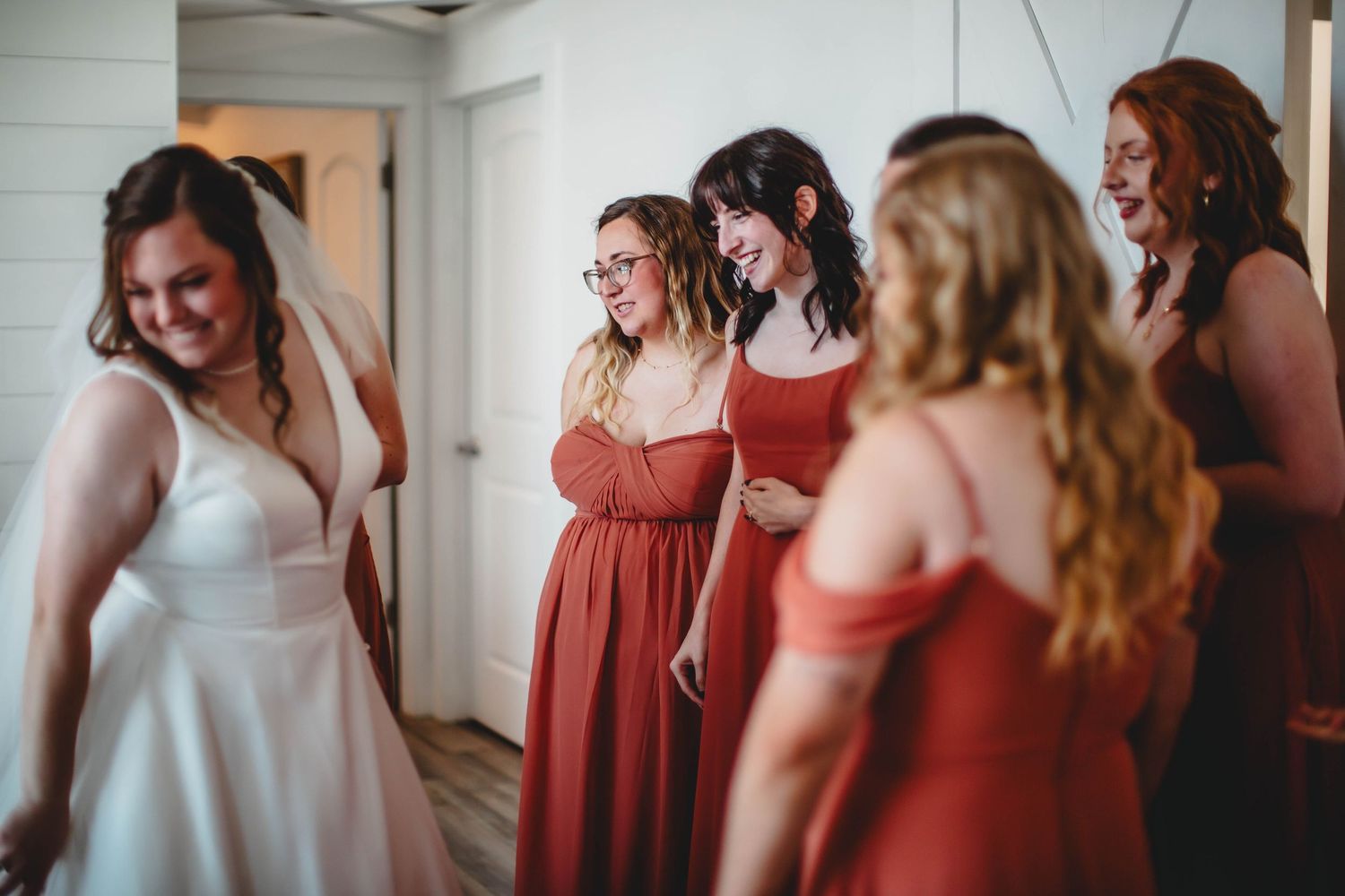 Bridal party wearing coral and white dresses standing together in an indoor venue.