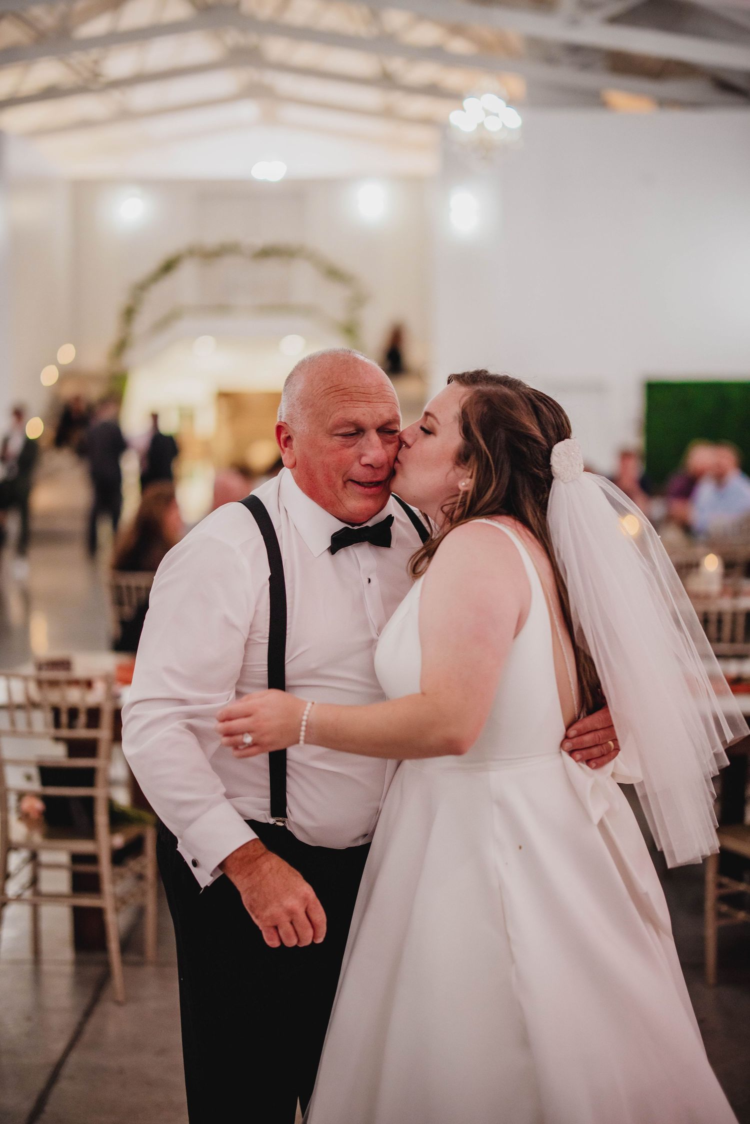 A tender moment captured between a bride and her dance partner during a wedding celebration.