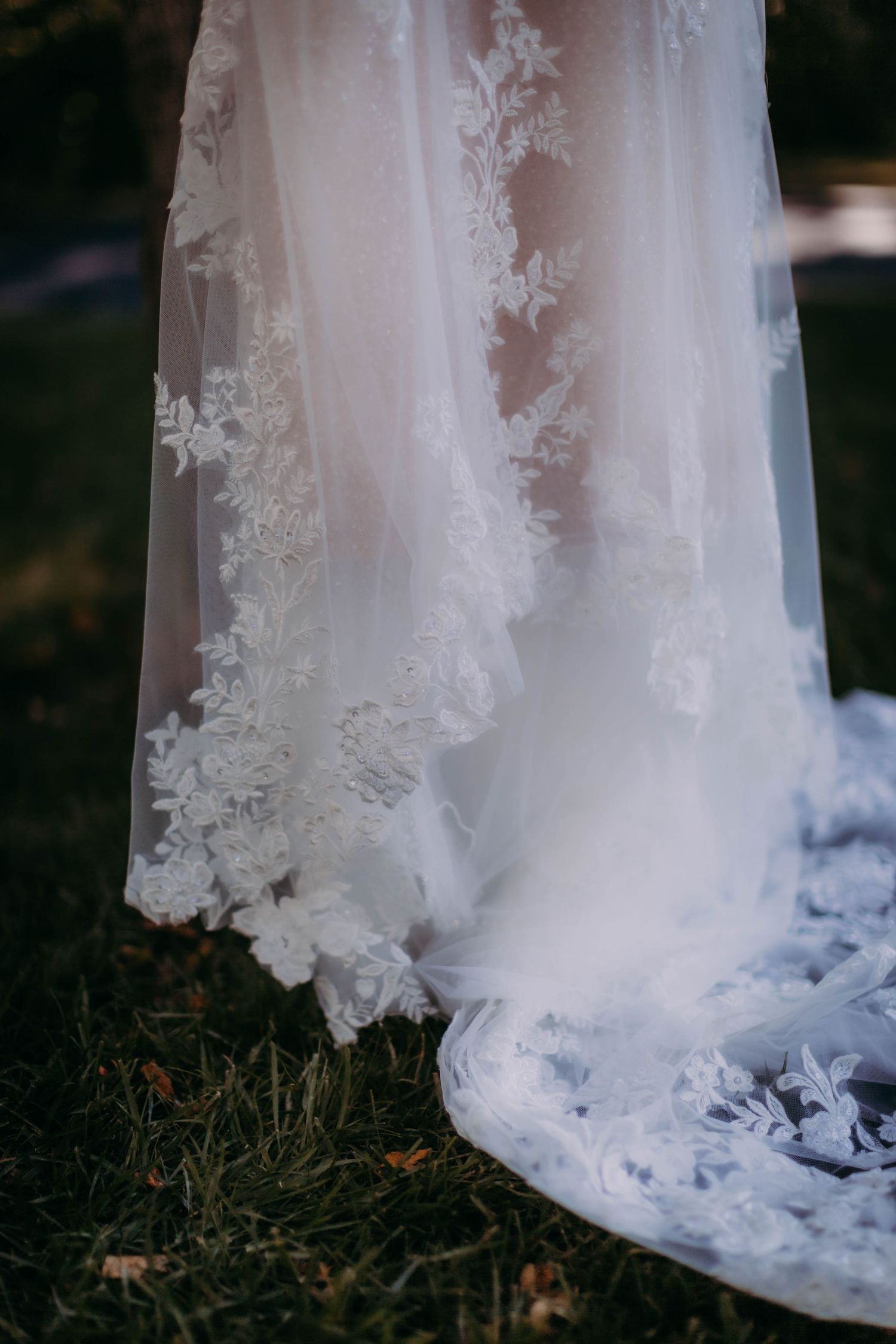 Close-up detail of delicate lace embellishments on a white wedding dress train.