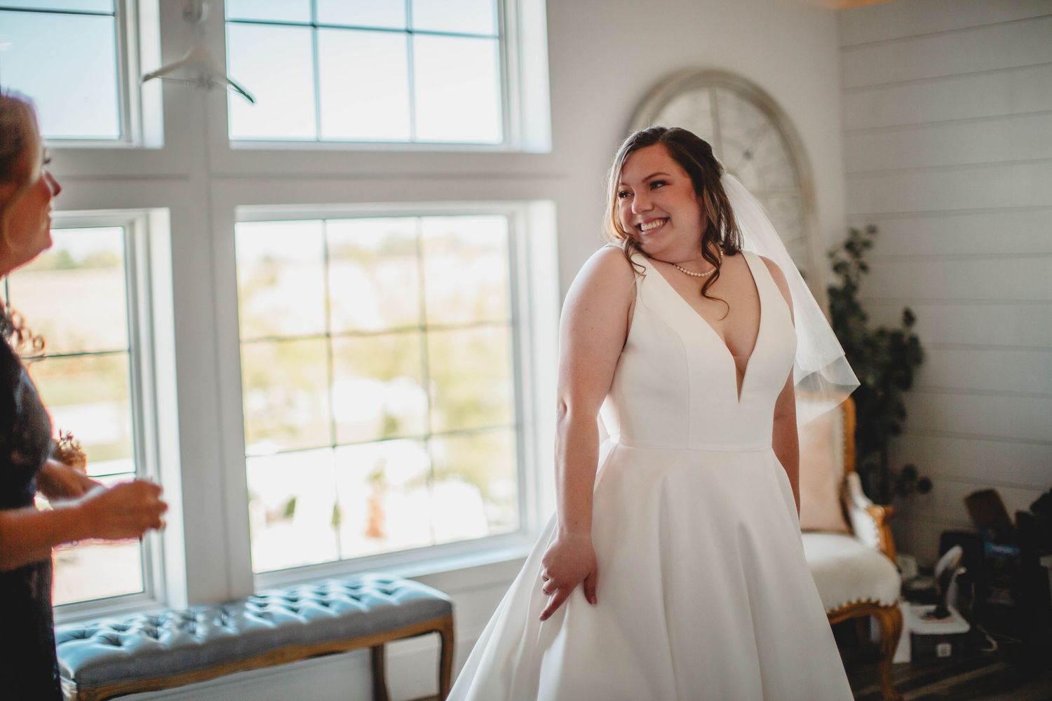 A candid moment of joy during wedding preparations in a bright, airy room.