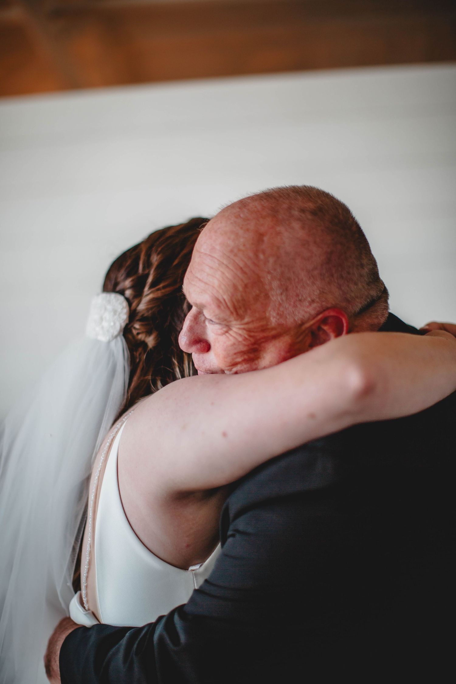 A touching embrace between two people at a wedding, with one wearing a flowing white dress.
