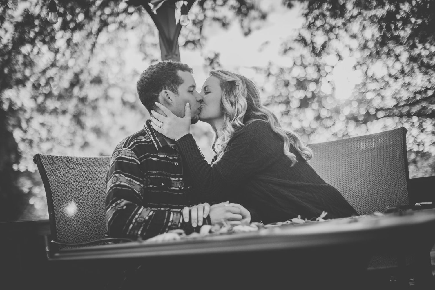 Two people share laughter while sitting at outdoor table in backyard.