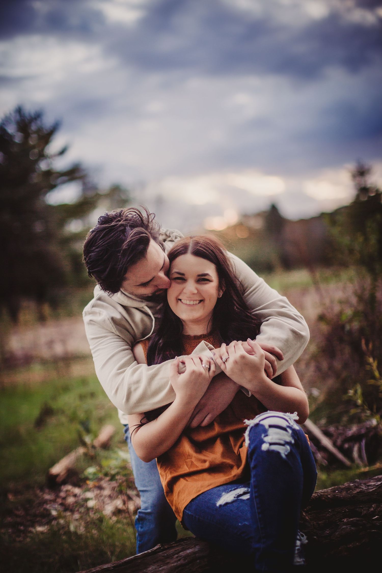 A romantic moment captured in the grass with warm lighting and dreamy atmosphere.