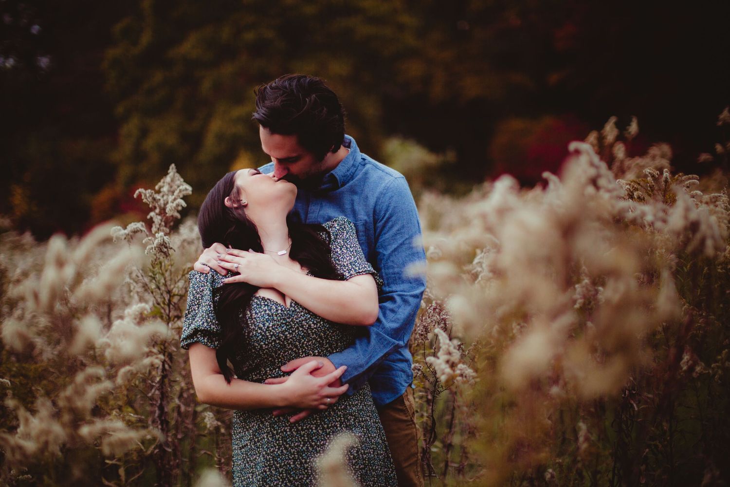 Romantic golden hour portrait of couple among wild autumn grasses.