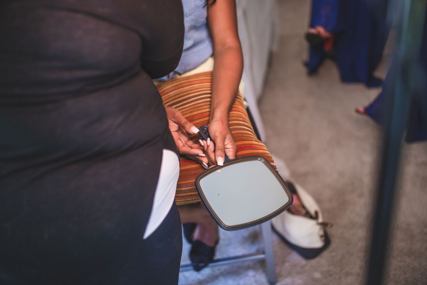 Person holding a makeup mirror during wedding preparations.