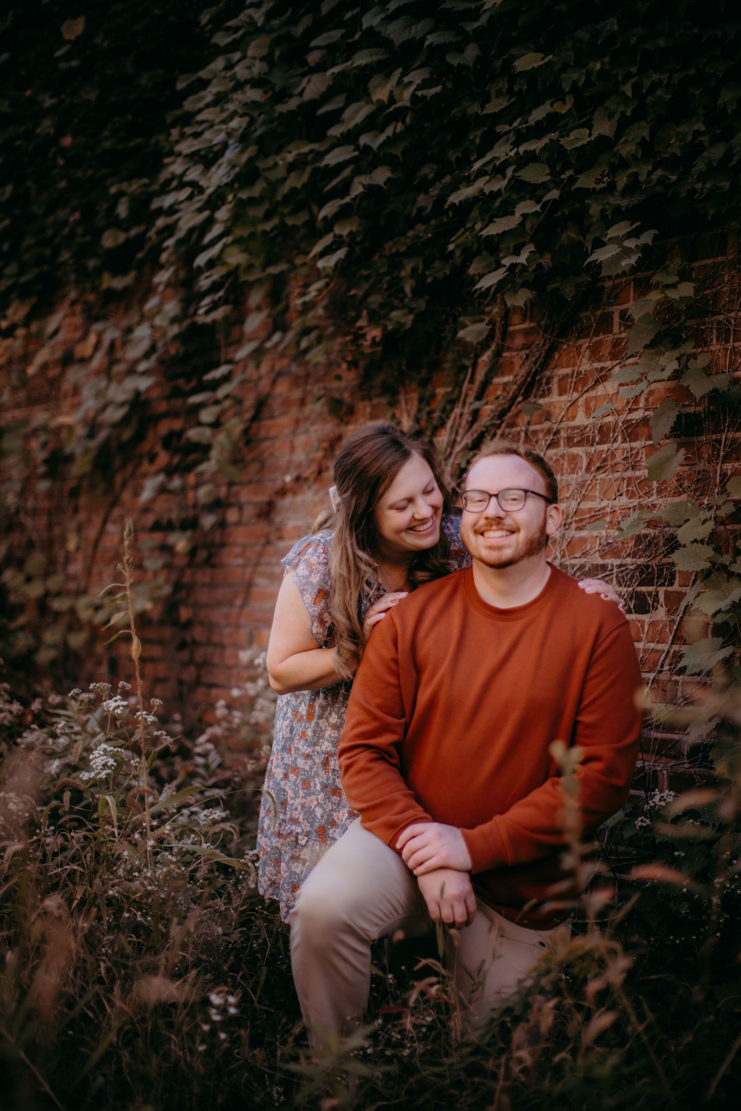 Natural lifestyle portrait of a couple enjoying a moment by a brick wall.