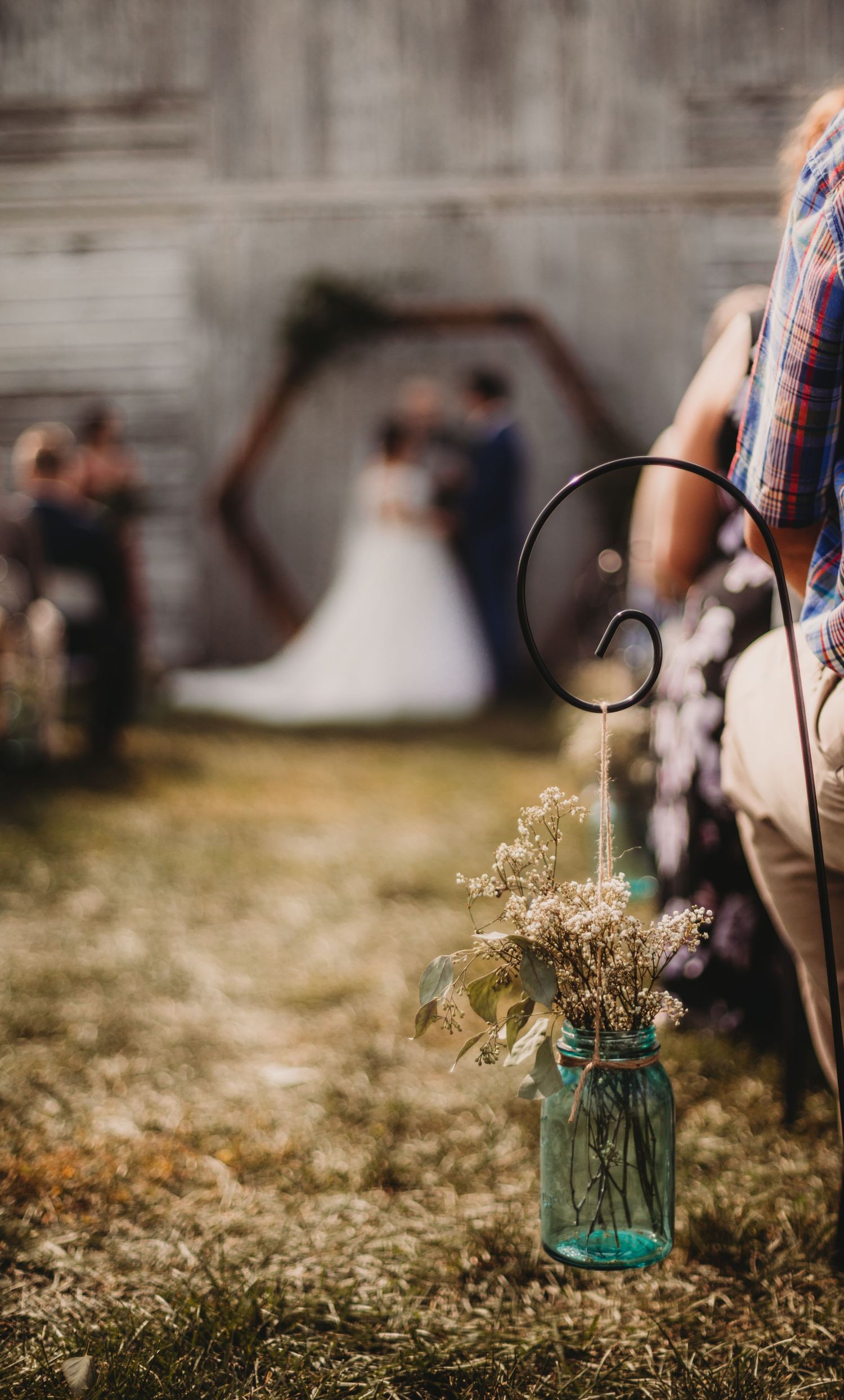 Blue mason jar with wildflowers decorates outdoor wedding venue.