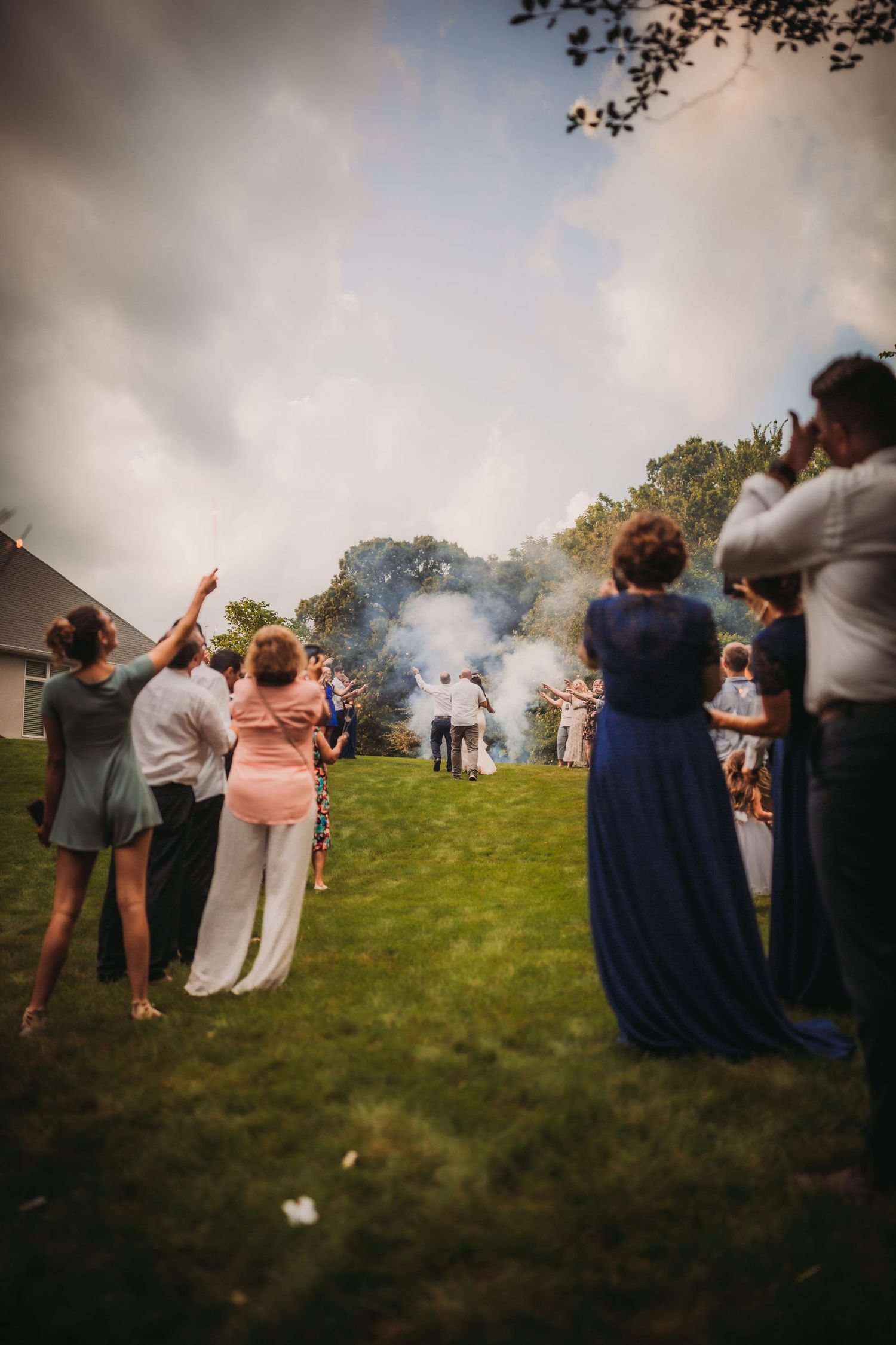 People in formal attire gather on a sloping lawn during a misty outdoor wedding event.