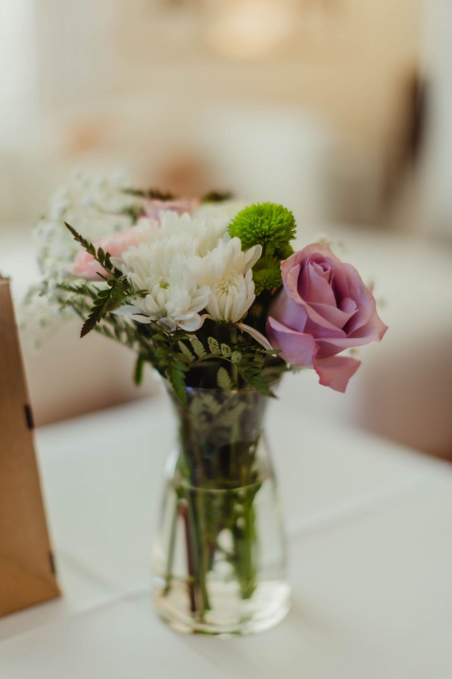 Small floral centerpiece with pink roses and white daisies in clear glass vase.
