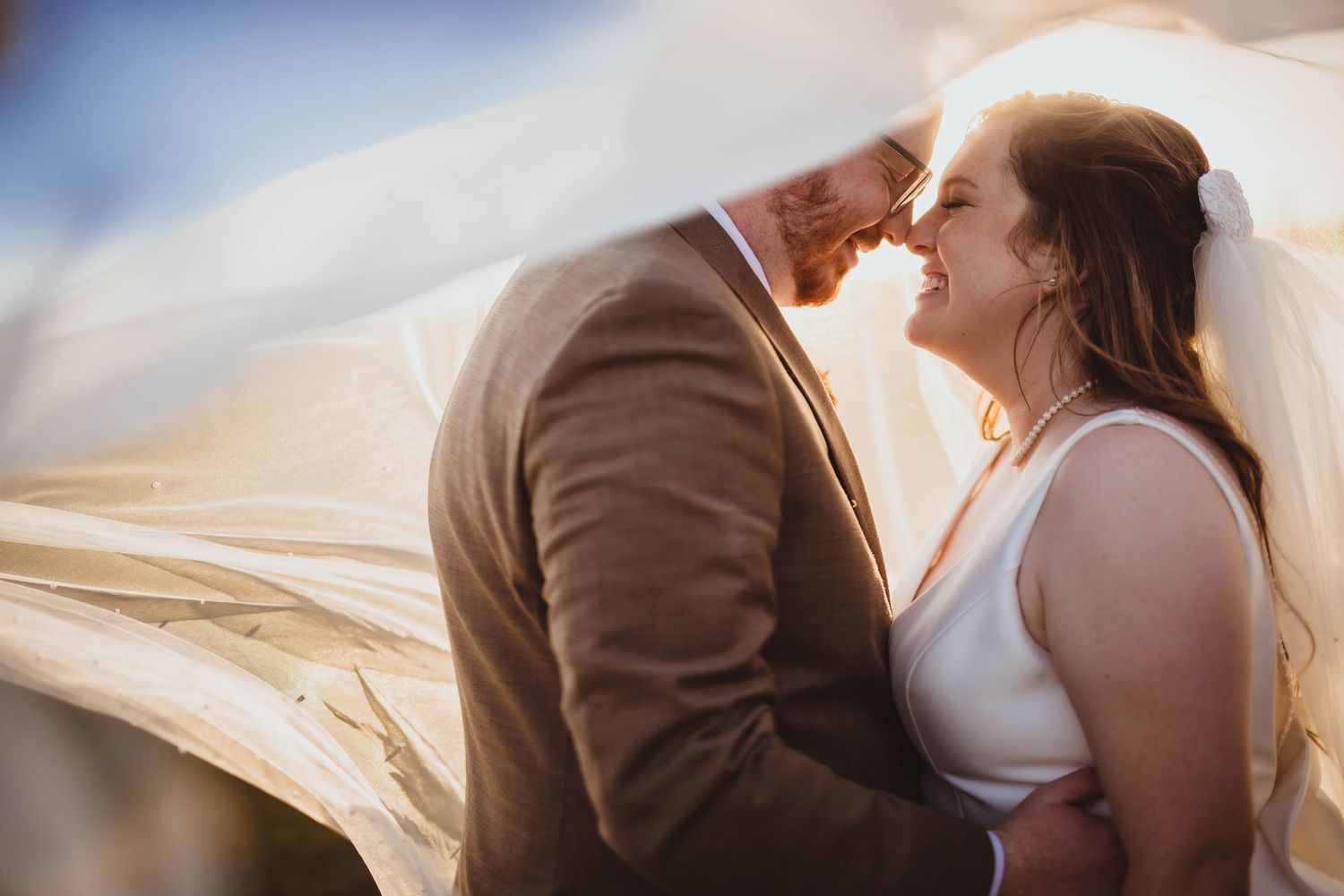 Romantic wedding portraits with billowing veil and soft natural lighting.