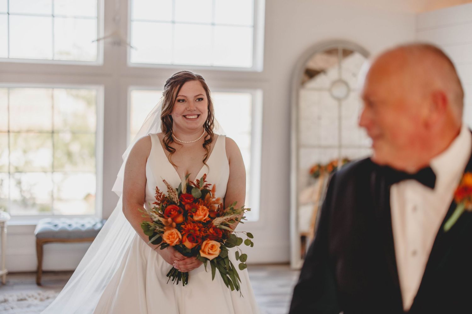 A joyful first look moment between a bride in white and groom at an elegant indoor wedding venue with bright windows.