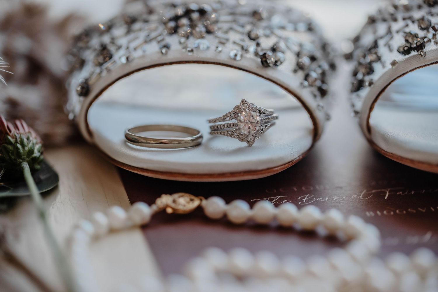 Wedding rings and pearls arranged on decorative mirrored trays.