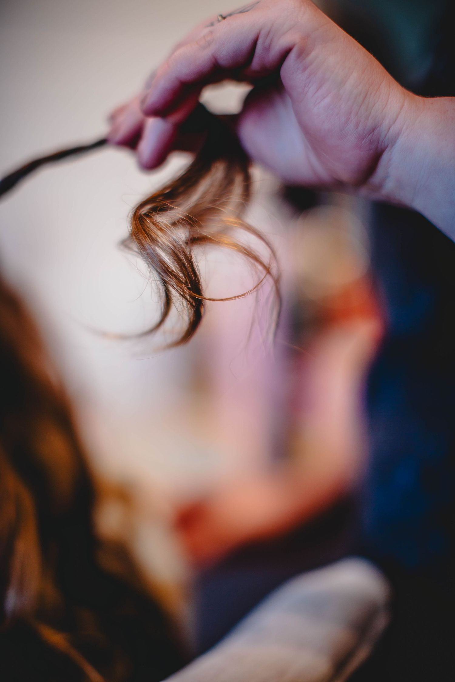 Close-up shot of hands styling a strand of brown hair.