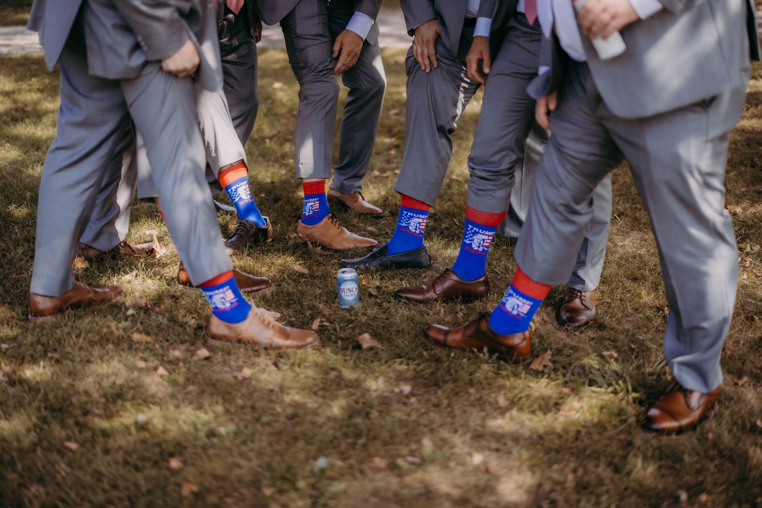 Groomsmen show off their colorful superhero socks while wearing grey suits.
