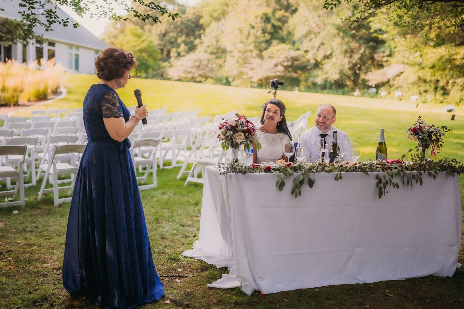 Nature-inspired wedding reception with white tables and navy accents in a garden setting.