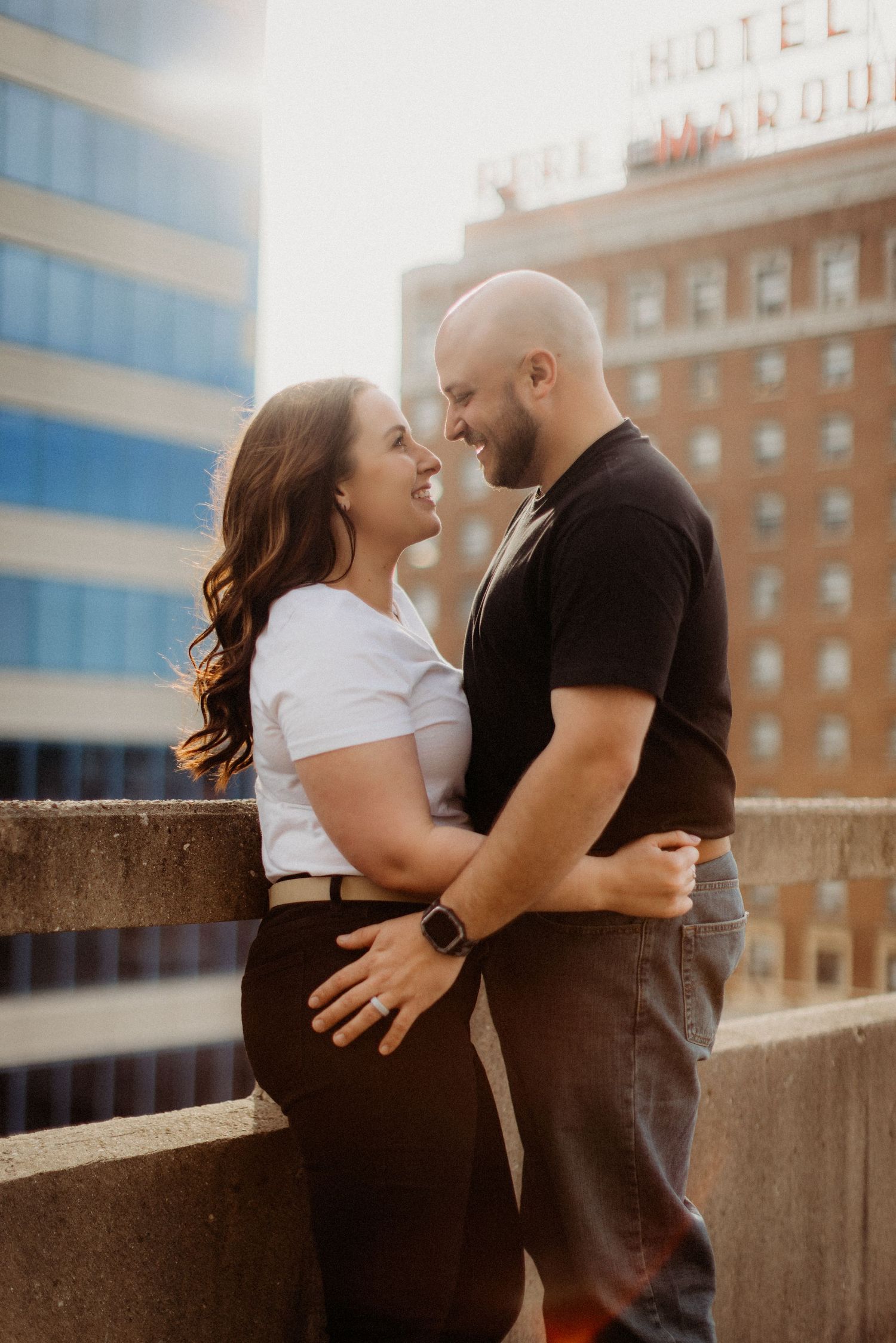An intimate moment between a couple posing against an urban backdrop at sunset.