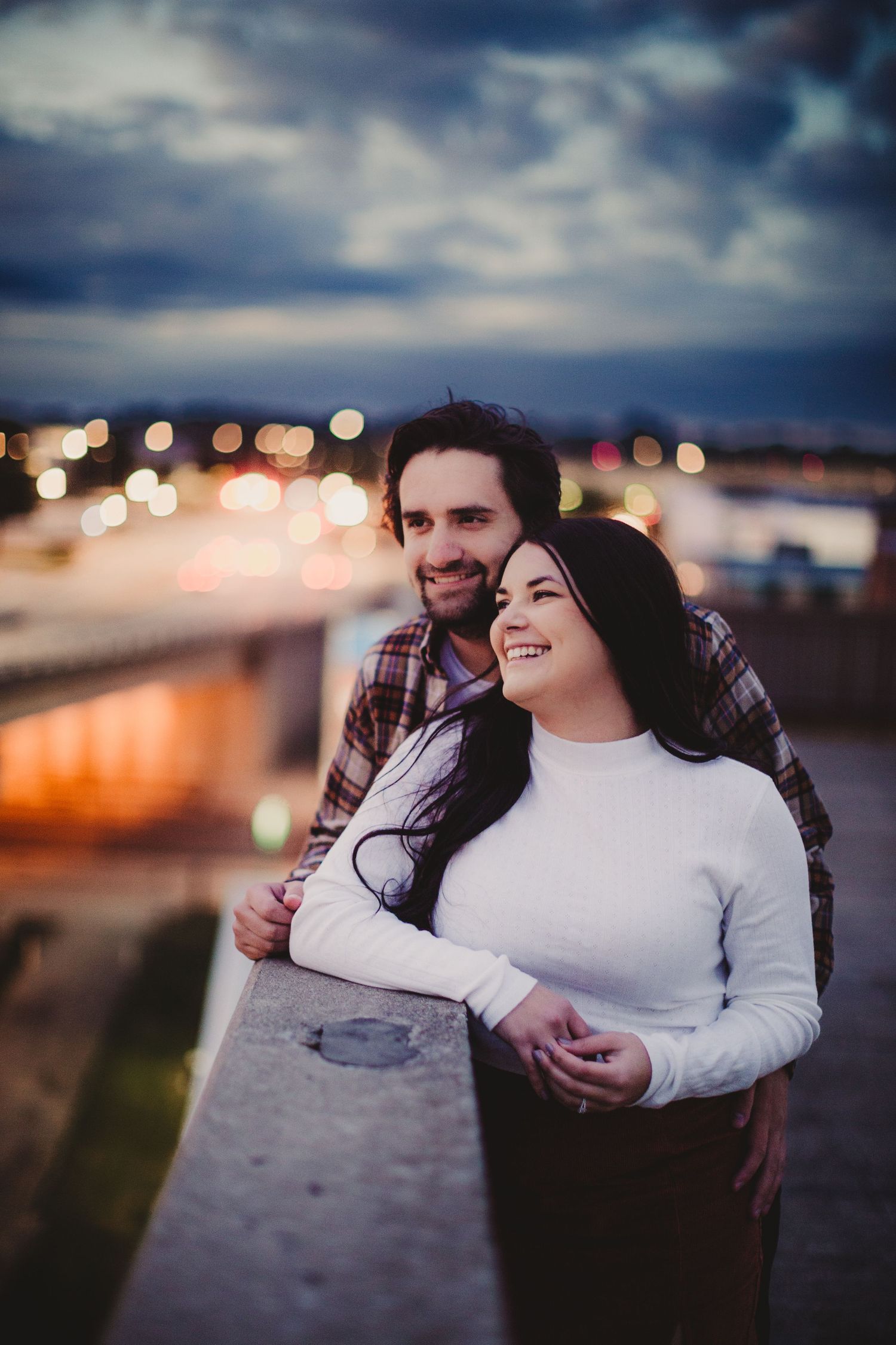 A couple shares an intimate moment at sunset overlooking city lights.
