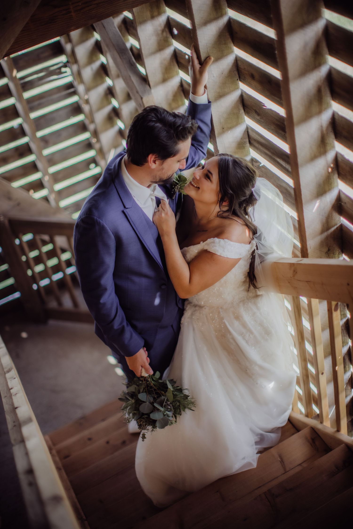 Happy wedding couple sharing an intimate moment on wooden steps with geometric patterns.