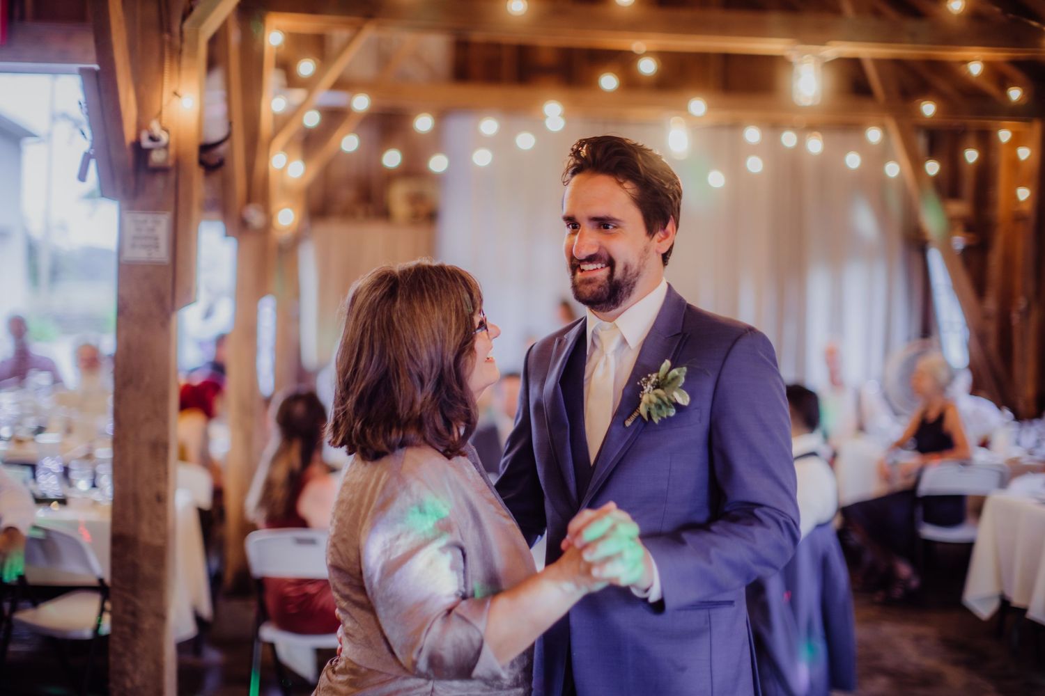 Couple dancing together during their wedding reception in a rustic barn venue.
