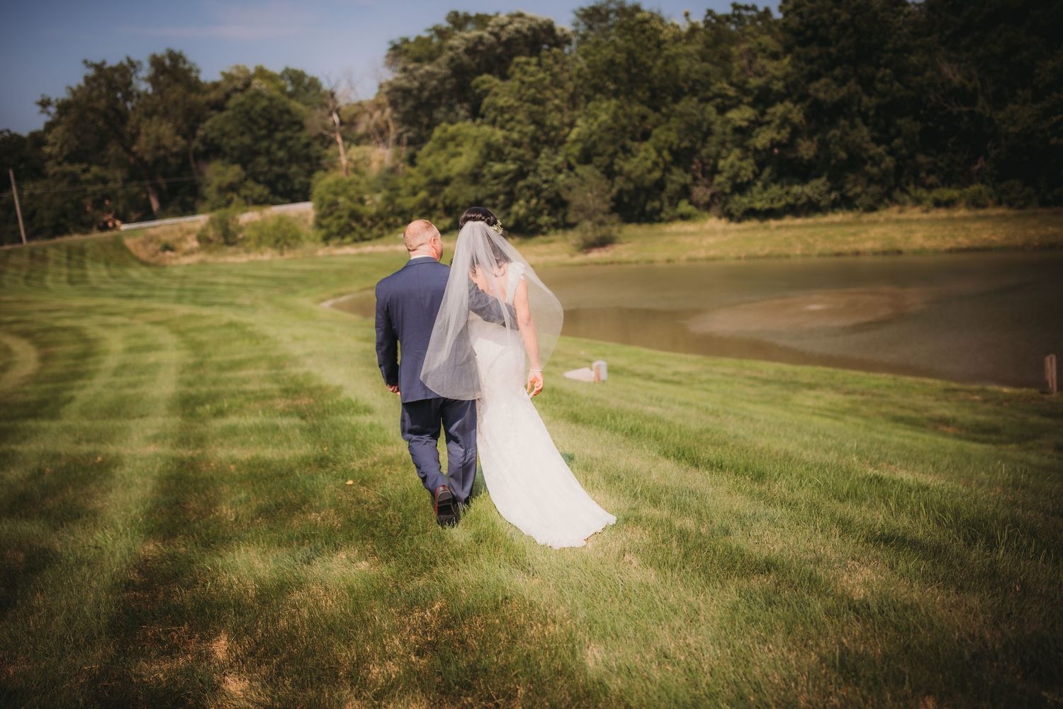 Couple walks away together across a scenic golf course on their wedding day.