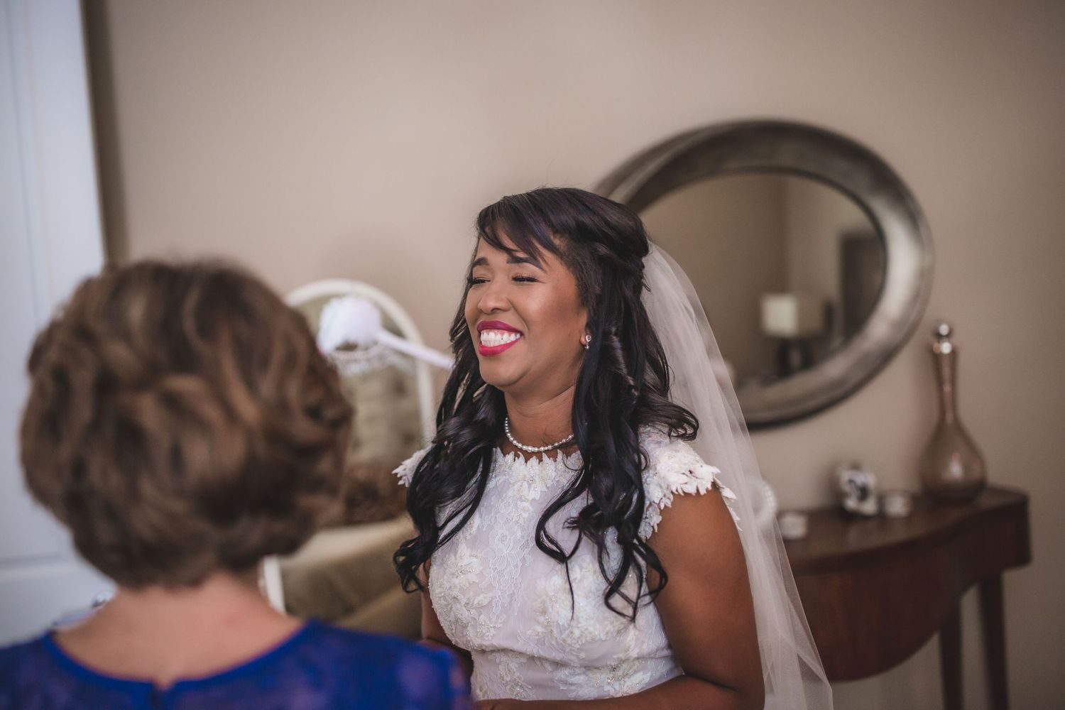 A joyful moment captured between a bride and wedding attendant during preparations.