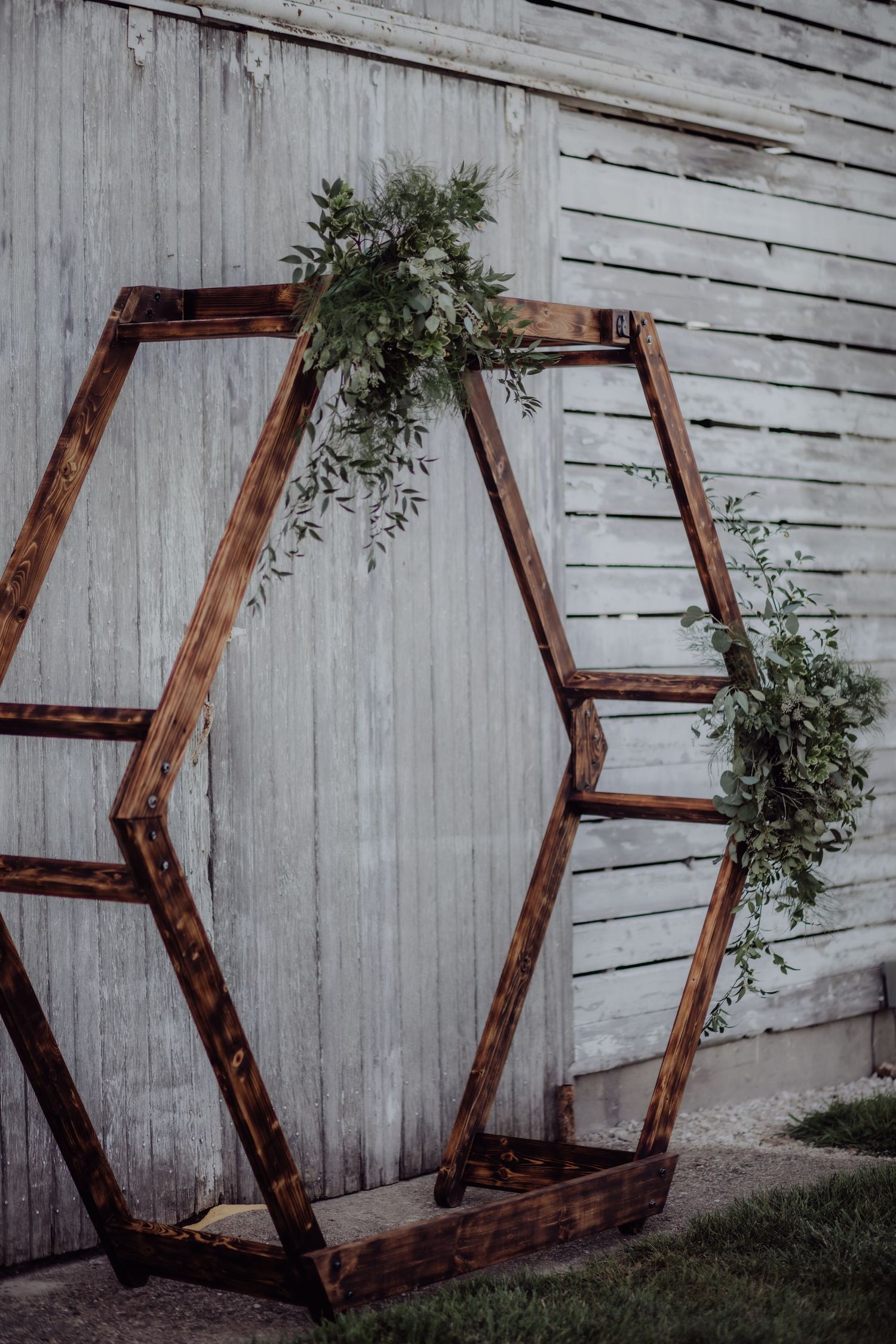 Geometric wooden hexagon shapes arranged against a white barn wall for wedding decor.