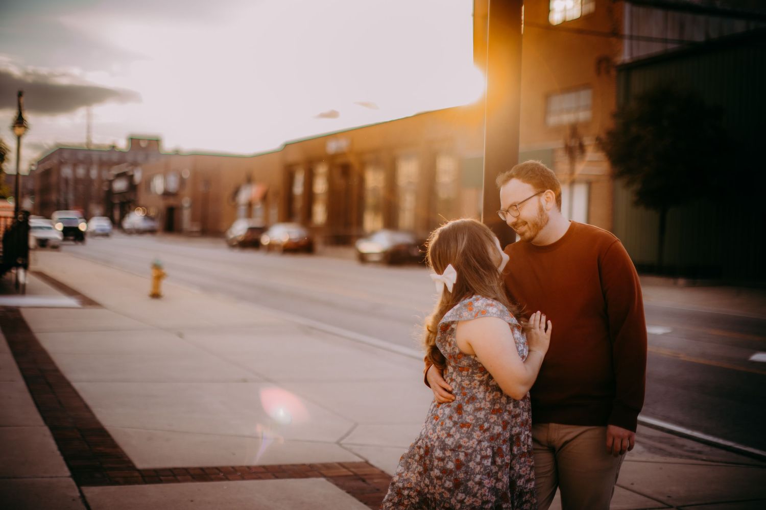 Golden hour engagement photos show a couple embracing on a quiet city street.