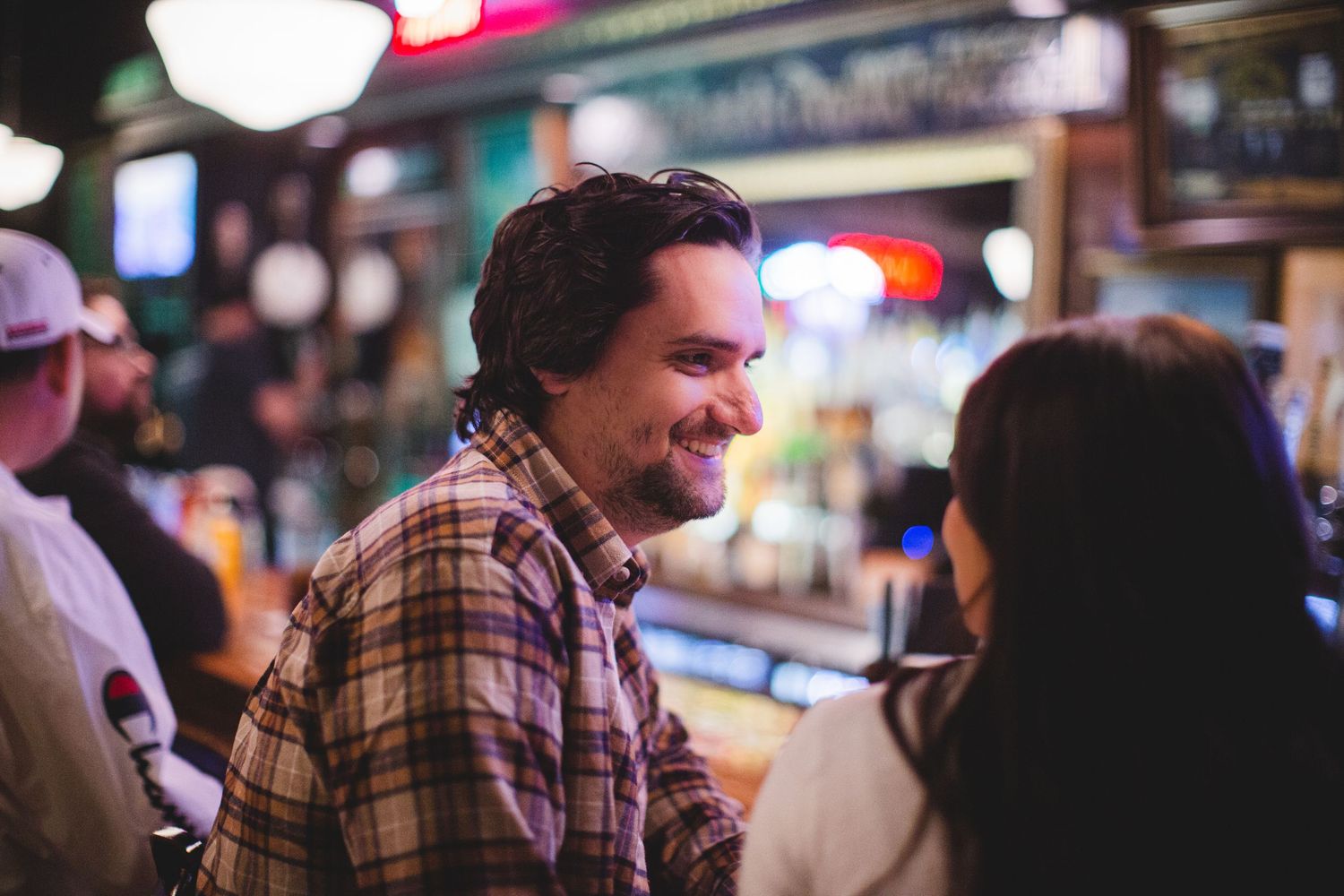 A couple sharing a candid moment of laughter together at a casual bar setting.